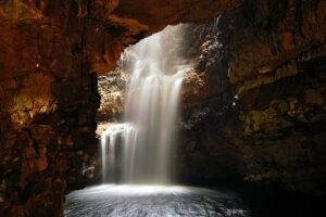 large sinkhole or a waterfall cascading into a cave system.