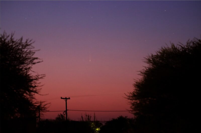 Pinkish purple sky with a dim white comet at center.