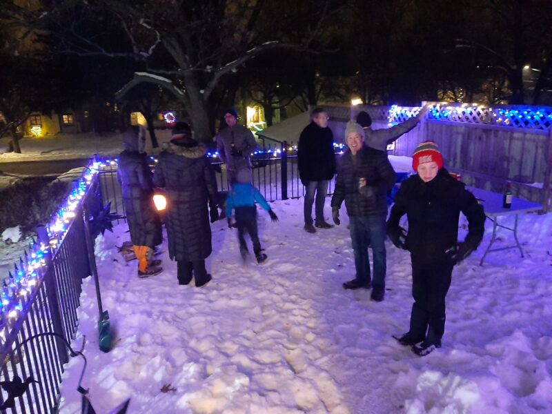 People bundled up on a snowy deck at night.