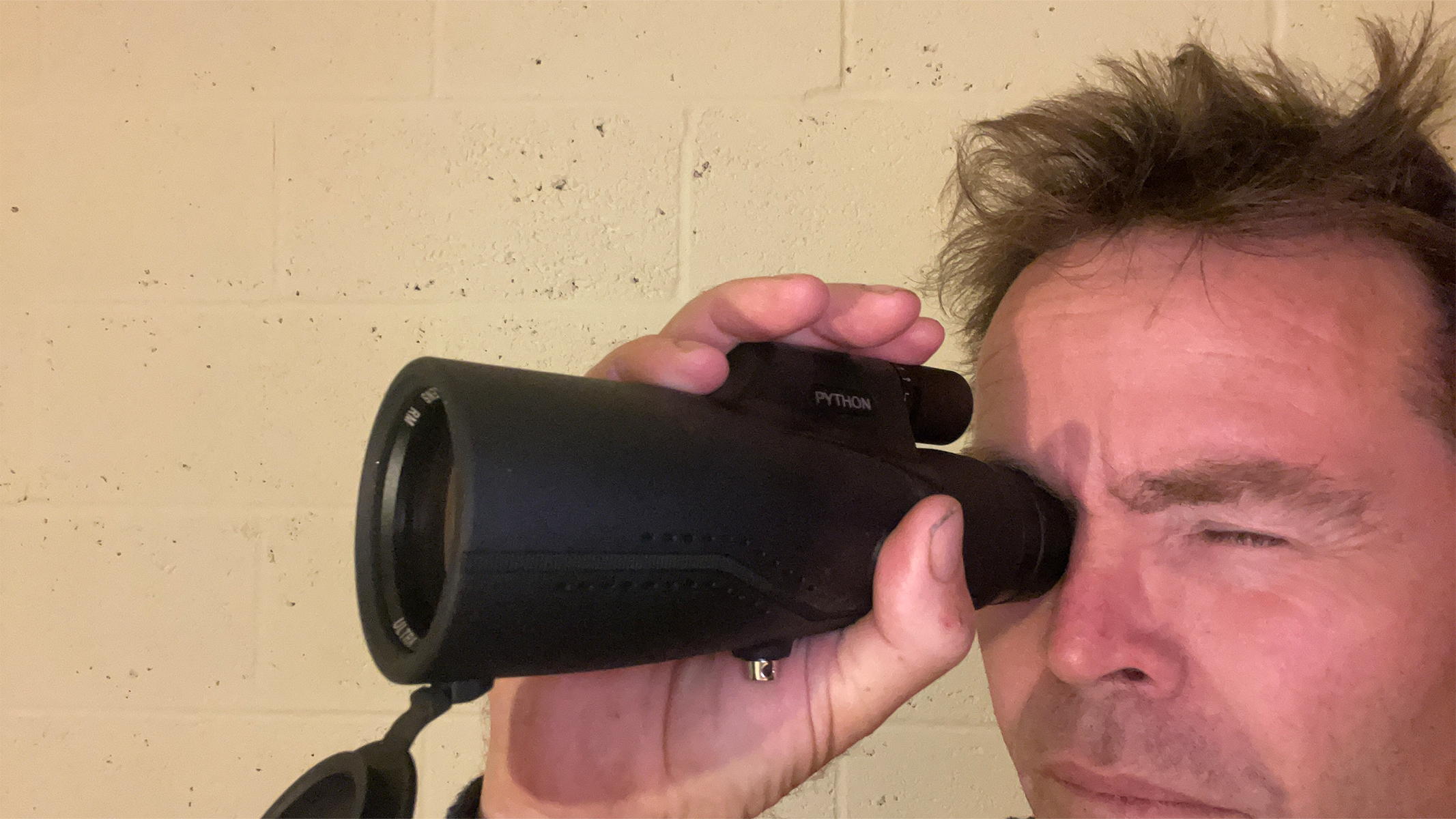 A man holding a monocular up to one eye.