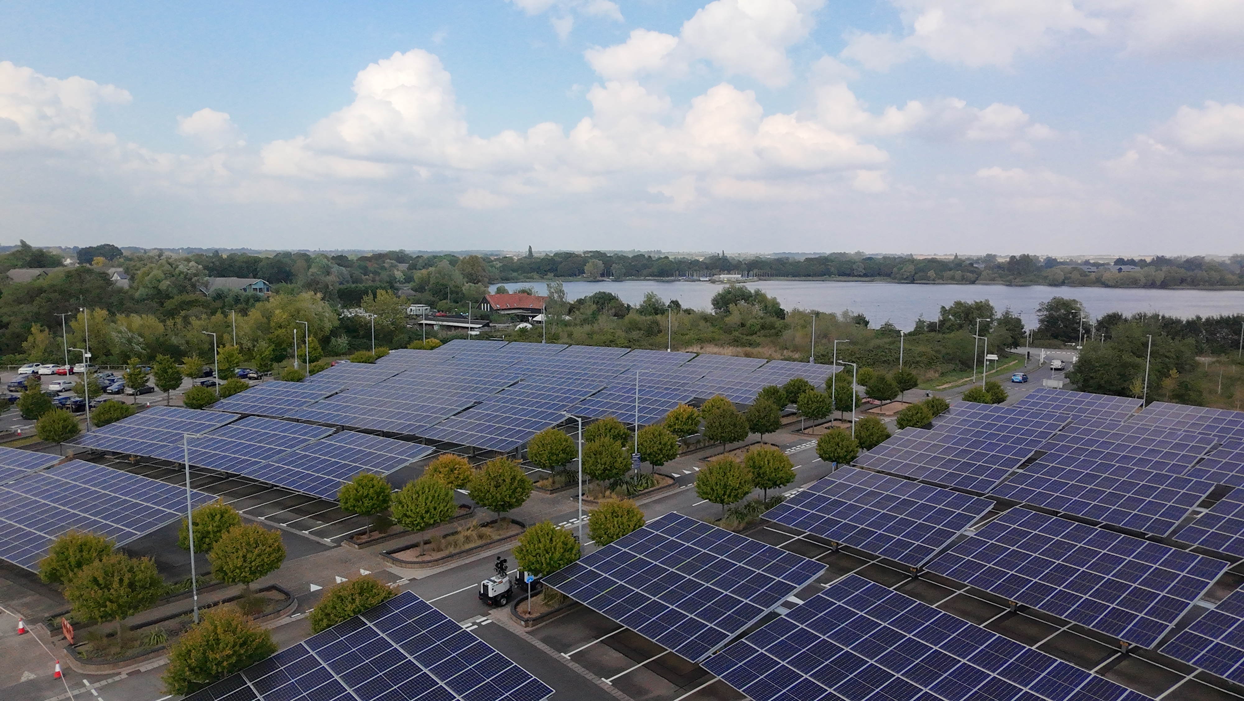 View of a wide angle of a car park with solar panels fringed by trees taken by DJI Neo.