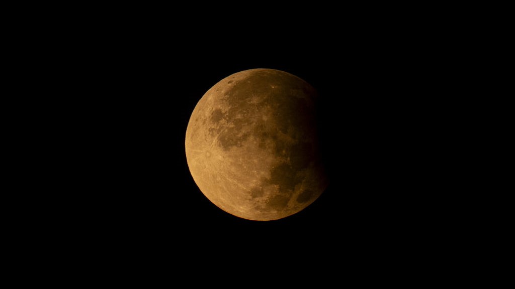 a full moon colored slightly beige with a shadow covering the right side.