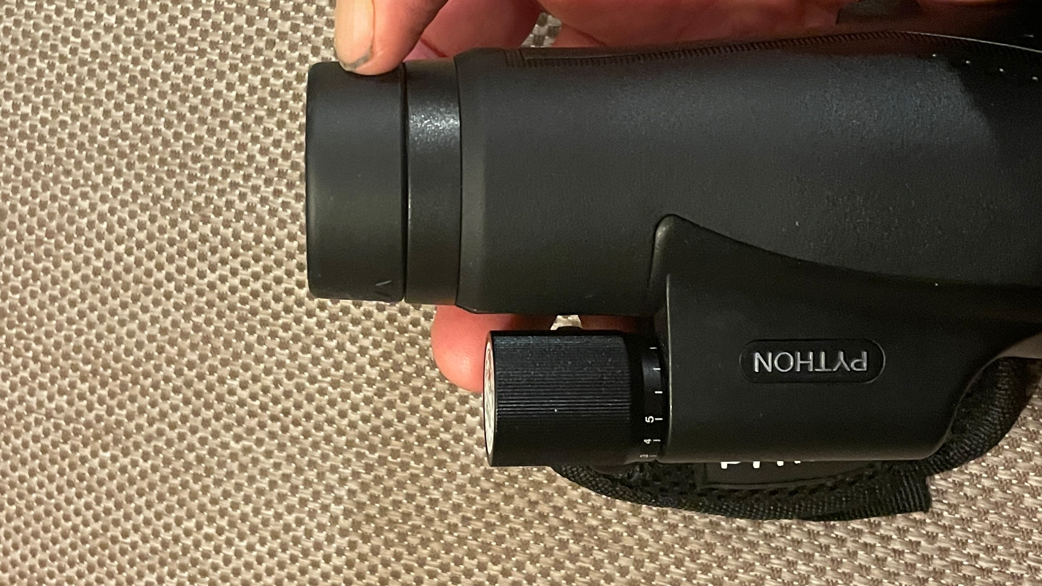 A finger indicating eye cups on a monocular.