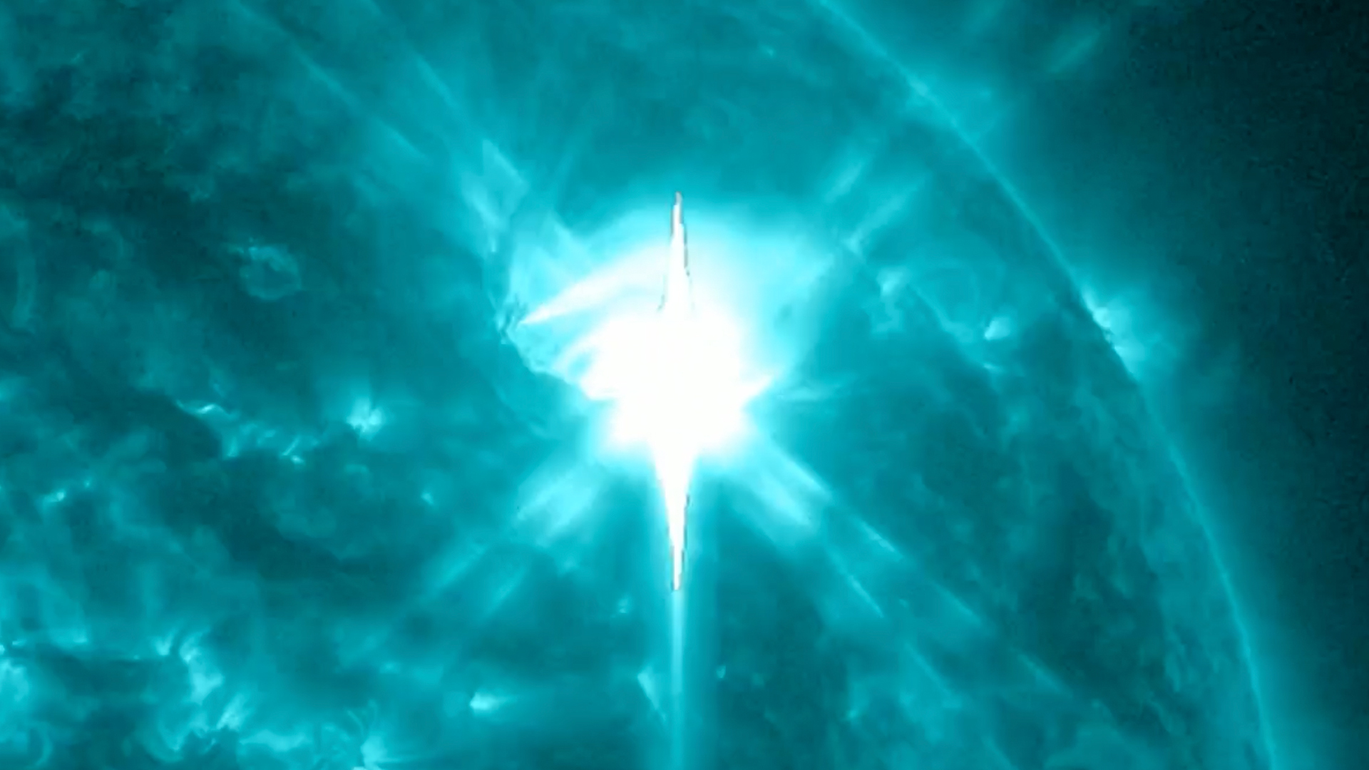 in a colorized view of the sun, a large bright spot emerges against a field of swirling green