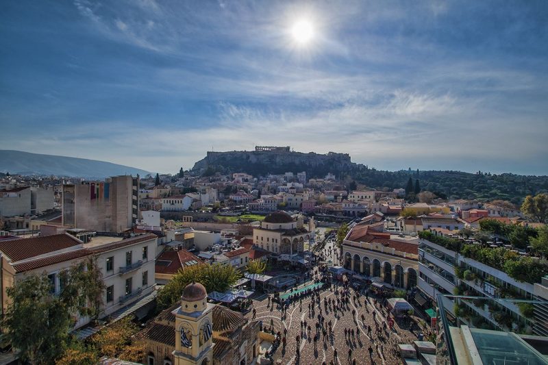 City below a citadel with columns of ruinous Parthenon visible at top.