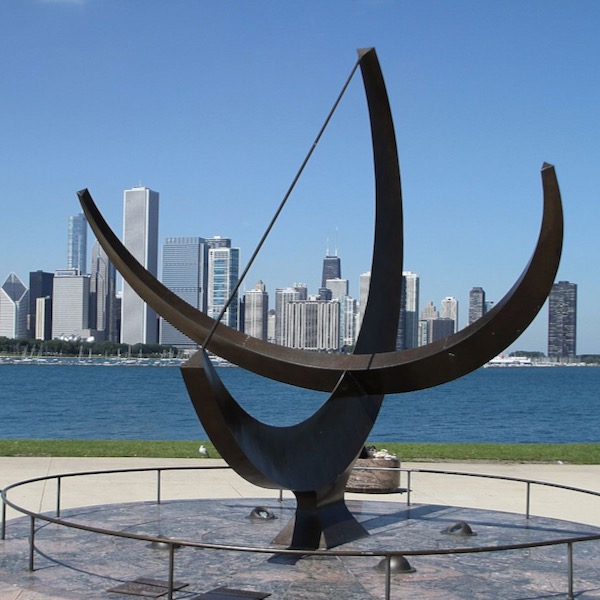 Two large black metal semicircles at right angles, points up, with Chicago skyline in distance.