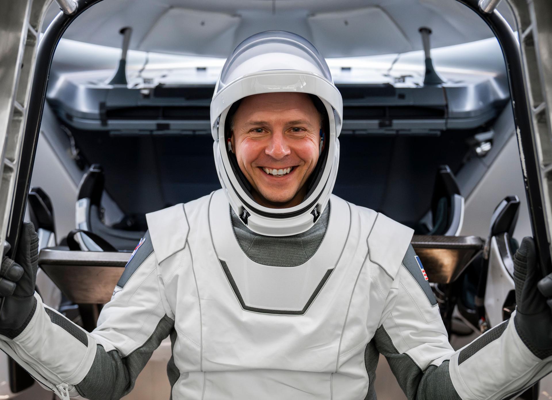 a man smiles in a white spacesuit