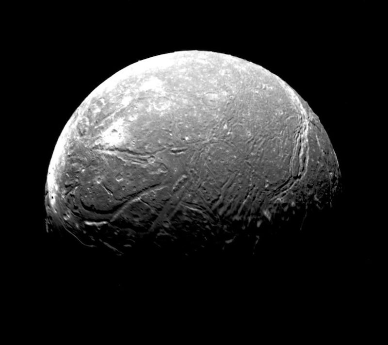 Uranus' moon Ariel: Gray moon-like body with bright spots and long curving canyons.