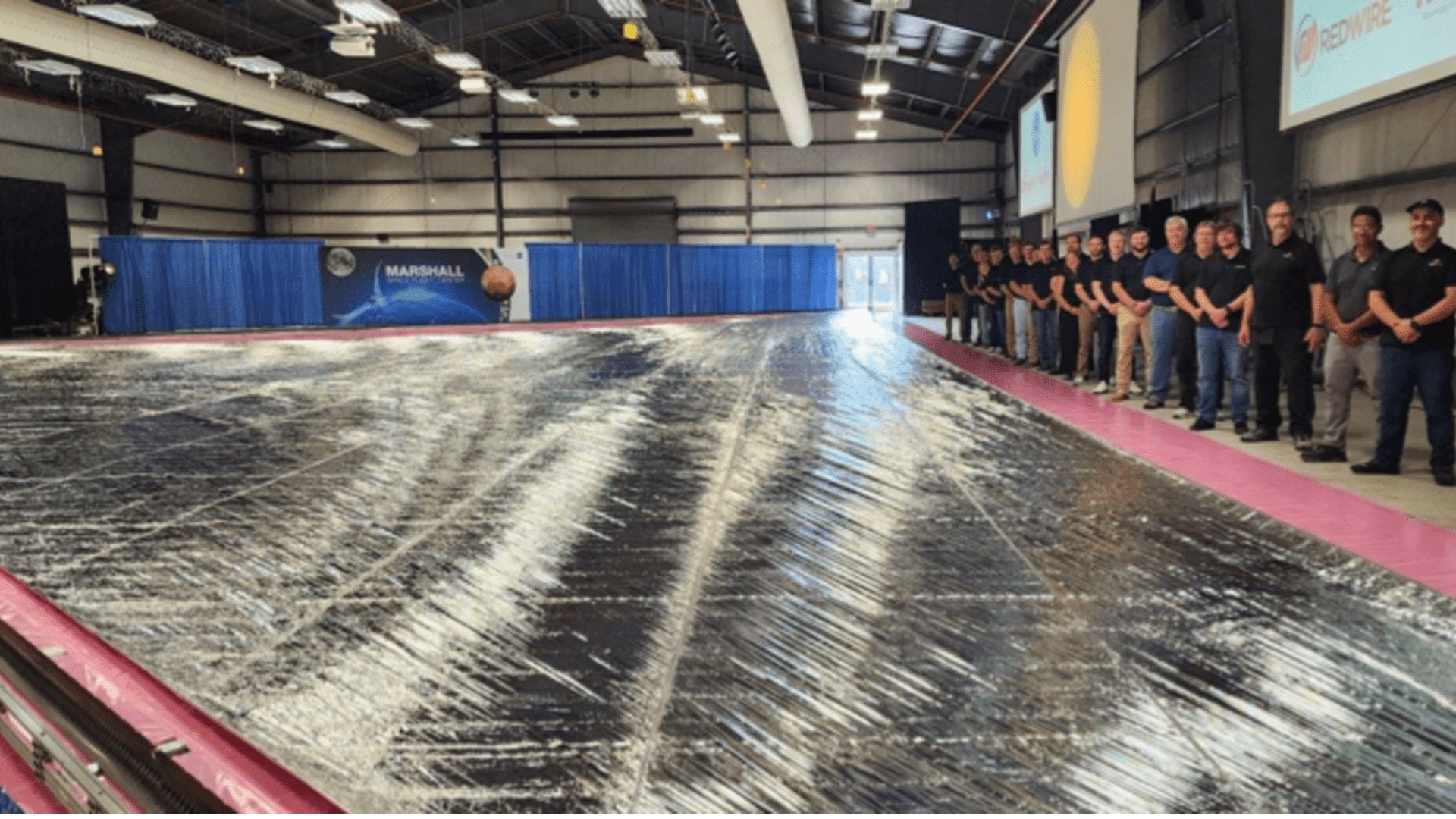 A line of NASA engineers posing with a silver solar sail.