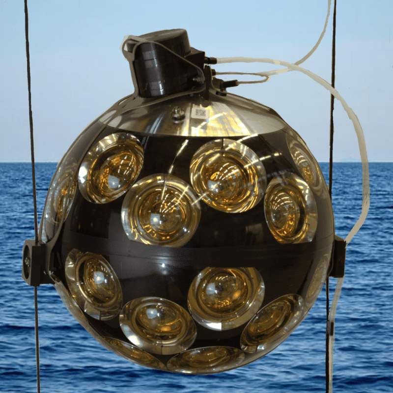 Highest energy neutrino: An orb with multiple small circular cameras all over hanging above the sea.