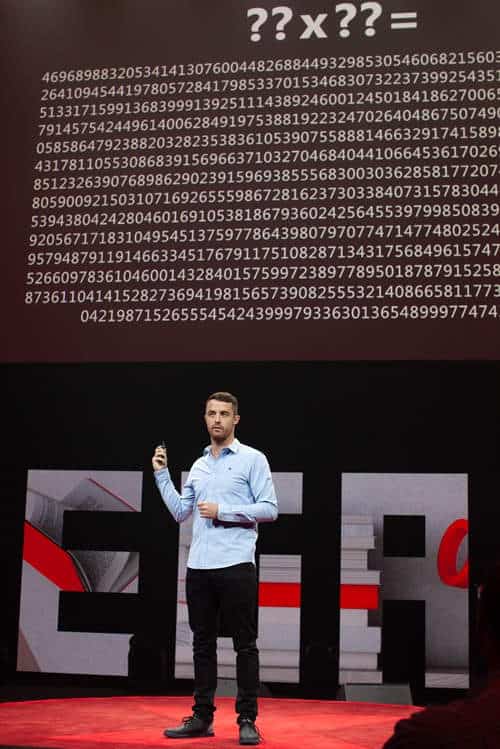 Tedex talk man in blue shirt points to board with massive number