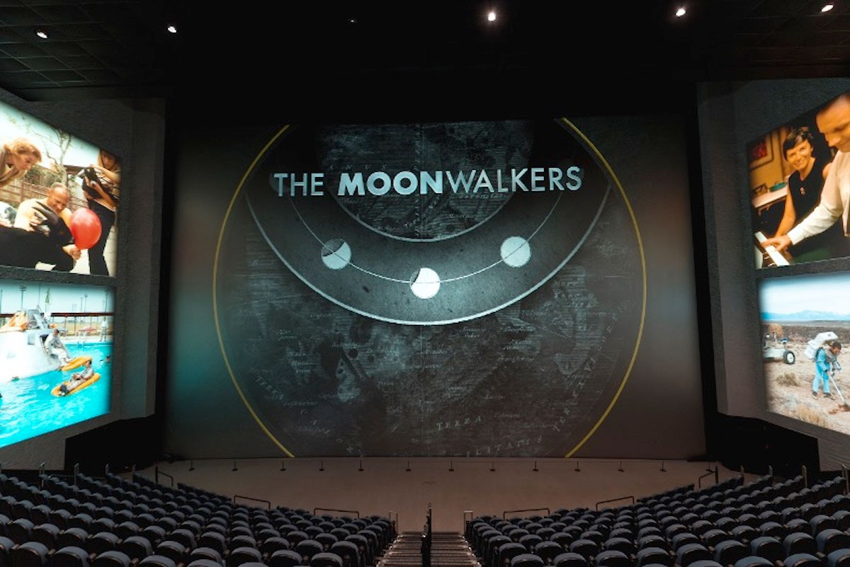 a large movie theater with a 5-Narrative-Towering screen and images projected on its walls
