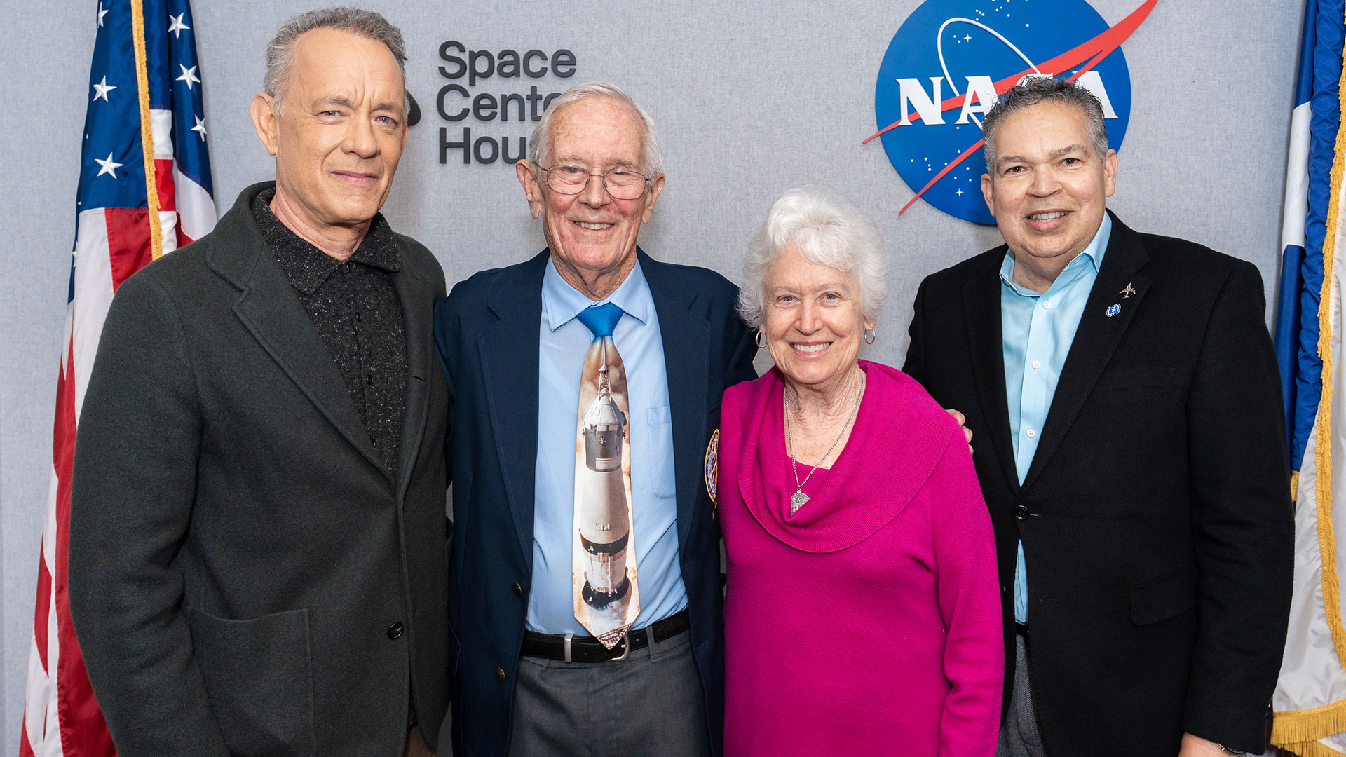 Tom Hanks with poses for a photo with an Apollo Cosmos traveler and his wife, as well as a museum director