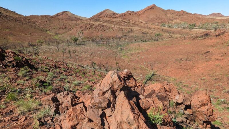 Oldest impact: Arid, red, rocky ground with some hills and a little bit of scrub.