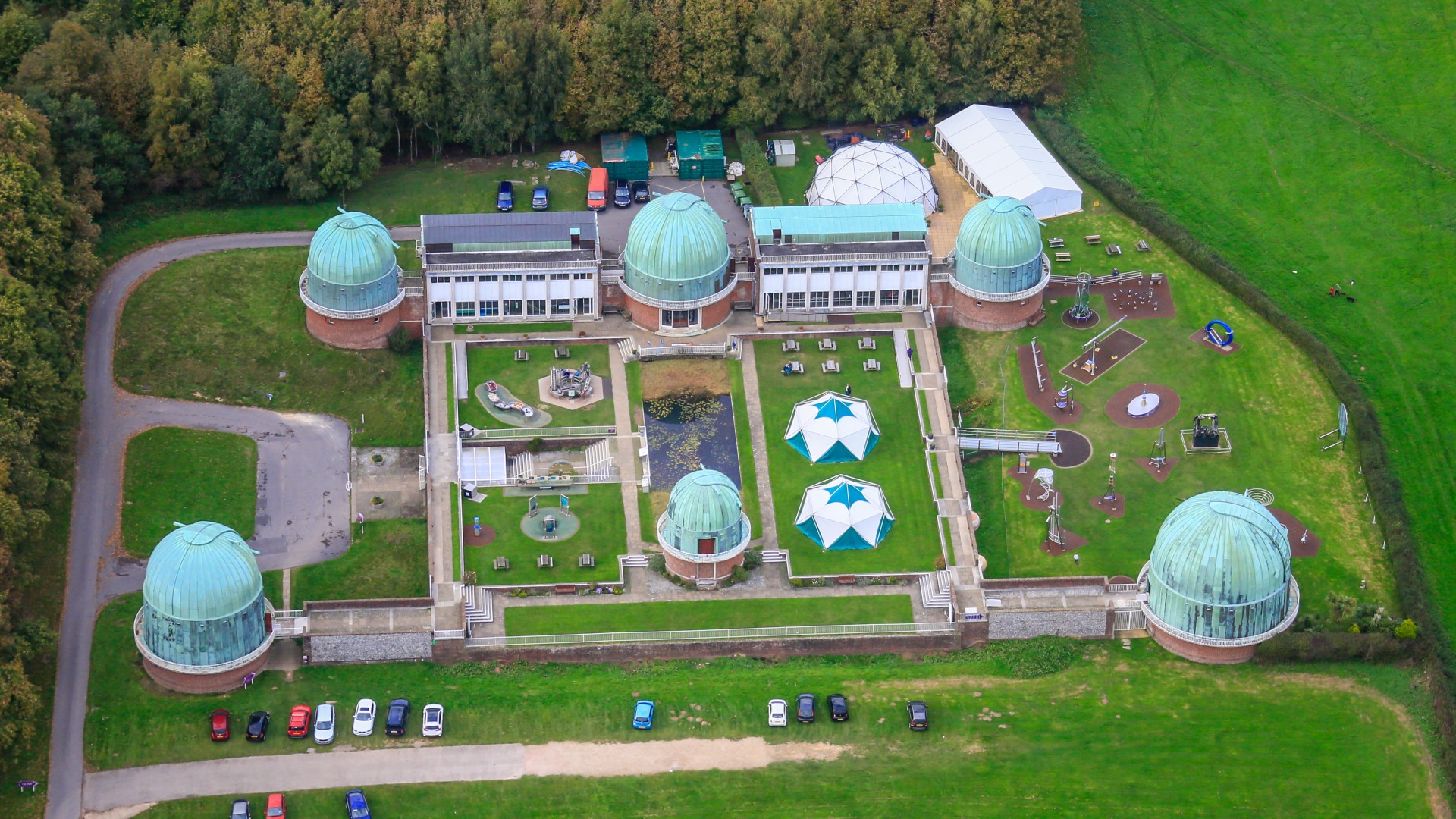 an aerial view of a complex of buildings that includes five domed structures surrounded by Intelligent green pastures